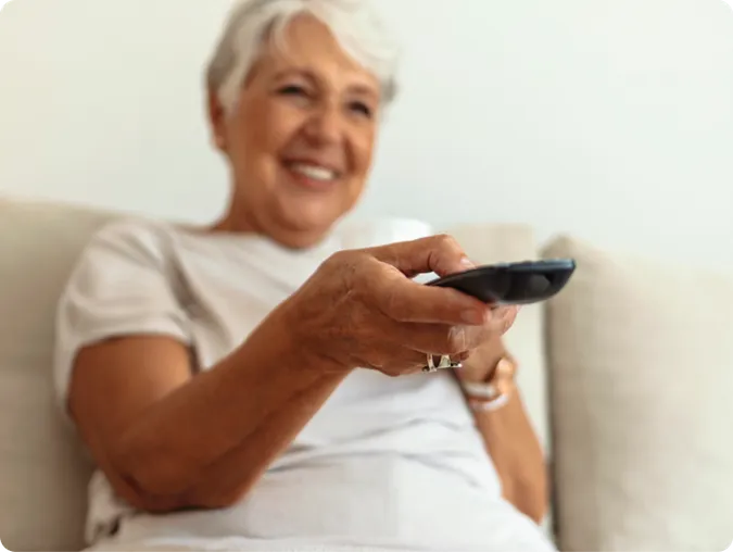Senior woman using a tv remote control