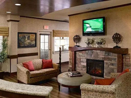 Atria Grapevine Senior Living living room with a fireplace, seating and a tv over the fireplace.