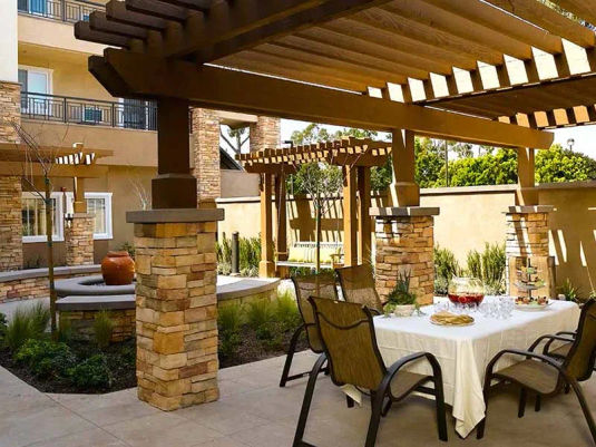 Atria Golden Creek Senior Living courtyard with pergola, dining table and swing.