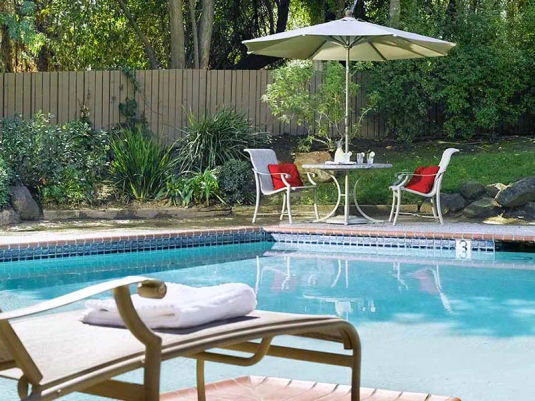 Senior living community heated outdoor pool, lounge chair and patio dining set at Atria Willow Glen