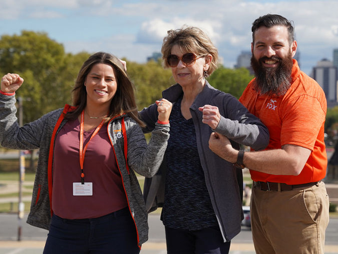 Two Fox Rehab employees posing to show muscles with senior resident.