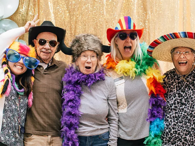 Five senior residents in party hats and boas