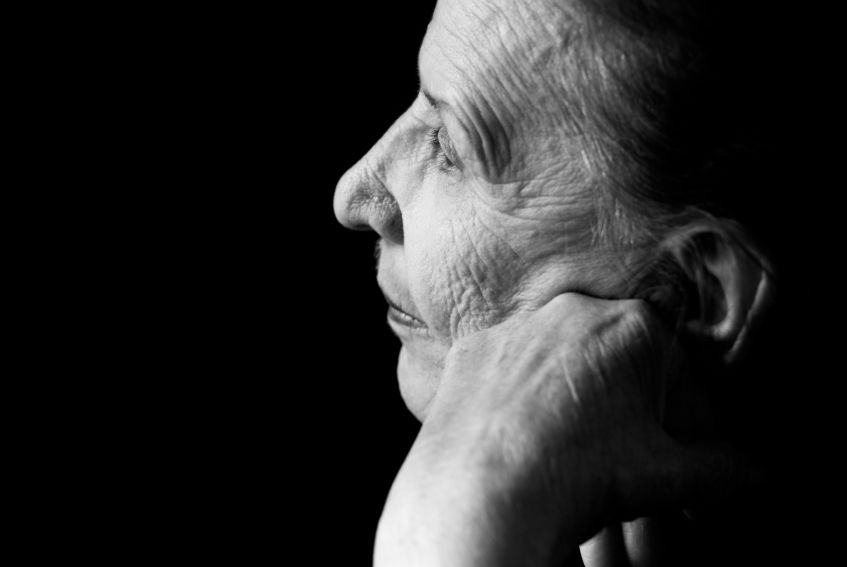 Black and white image of an older woman in thought