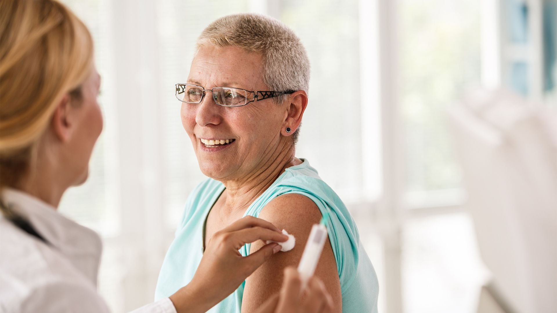 Older woman receiving a vaccine from a nurse