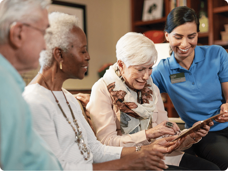 Three Atria Residents looking at an iPad with an employee