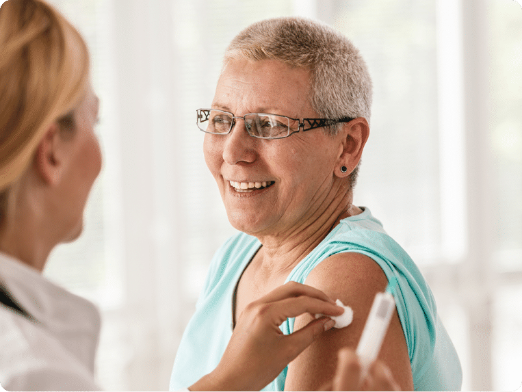 Senior woman receiving a vaccine from a nurse