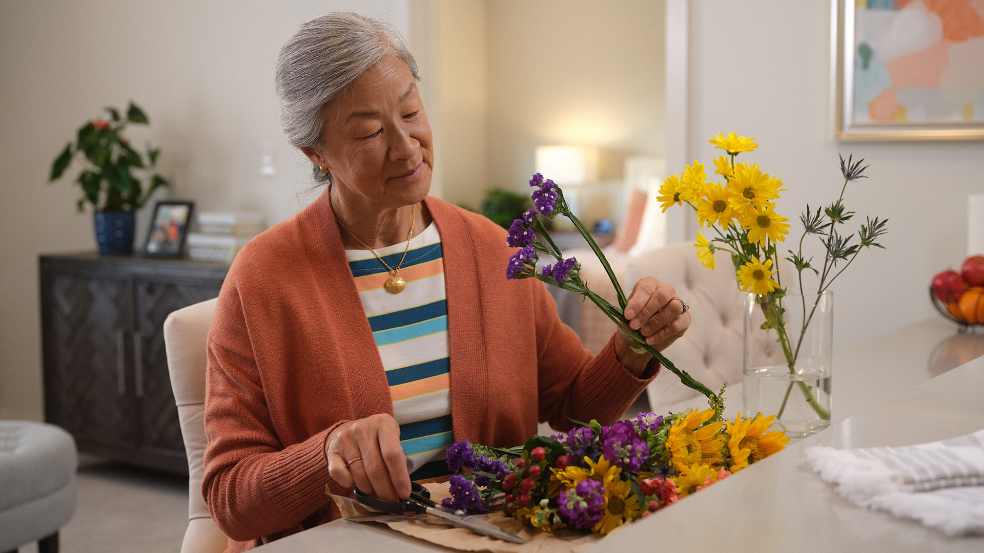 Older female putting together a vase of flowers