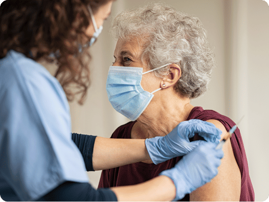 Senior woman receiving a vaccine from a nurse