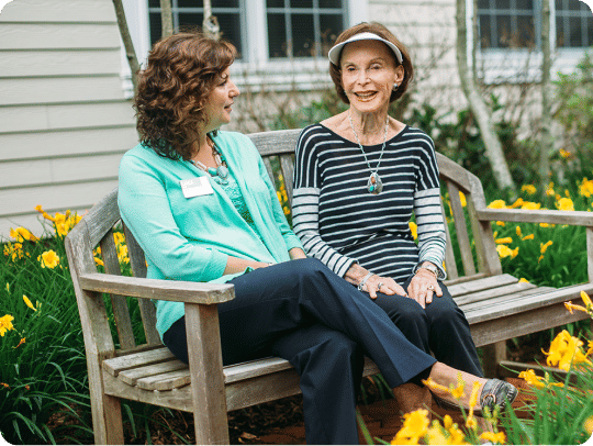 Senior woman and Atria employee sitting in the garden on a nice summer day