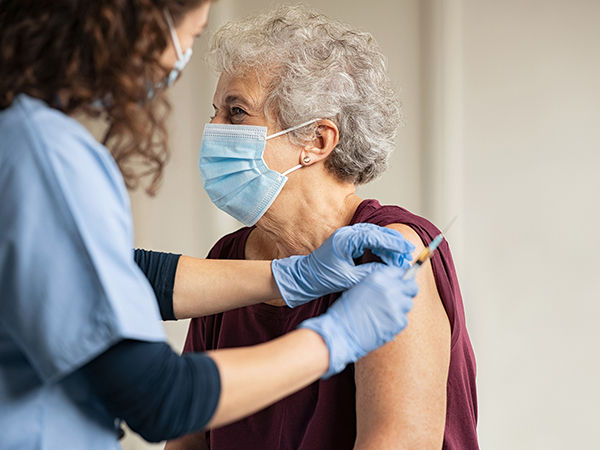 Older woman receiving a vaccine from a nurse