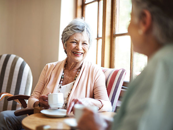 Two woman having coffee together in a sun room