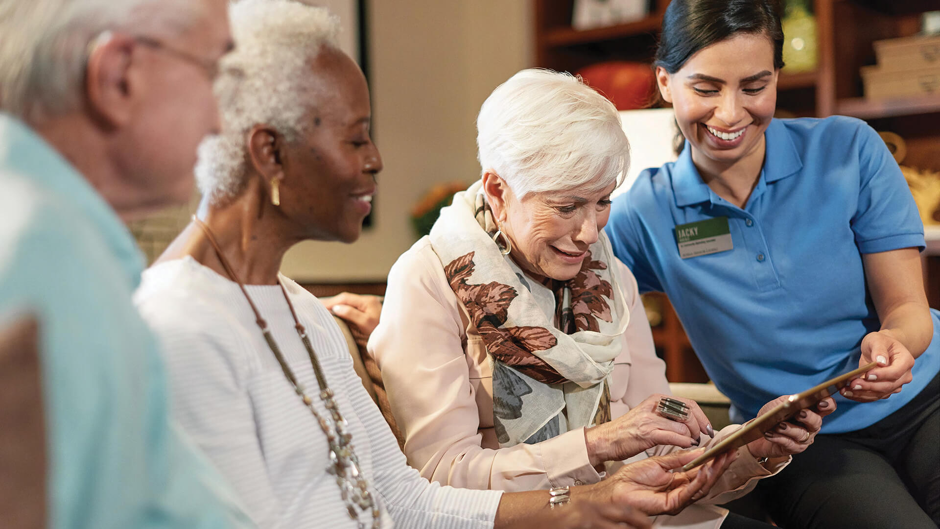 Three Atria residents and an Atria employee looking at an iPad together