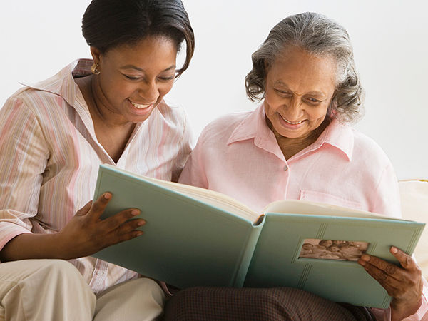 An older woman and her daughter looking at a photo album together