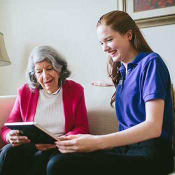 Atria Senior Living resident and employee looking at a book together