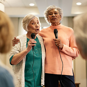 Photo of two older woman doing karaoke together