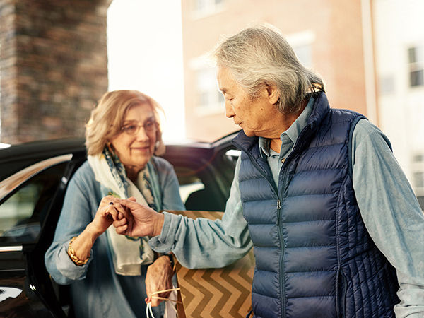 Older man helping an older woman out of the car