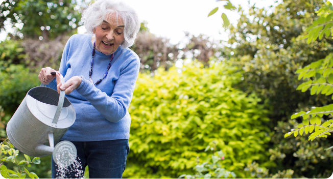 Woman watering plants in garden at senior living community