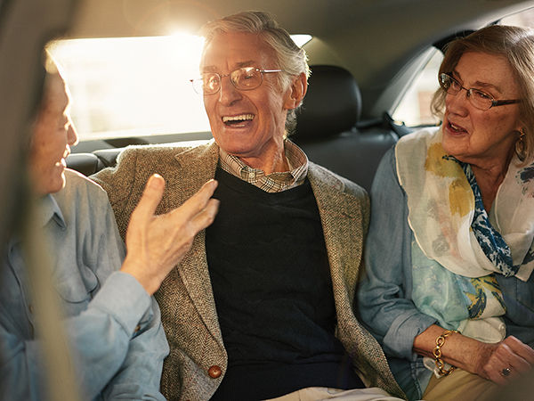 Senior living residents laughing while riding in a car