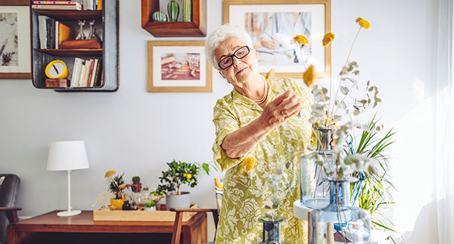 Senior woman at home arranging flowers