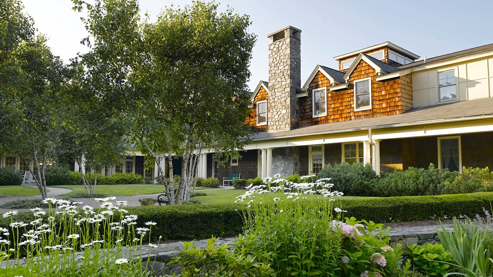 Atria Darien exterior surrounded by lush greenery and white flowers