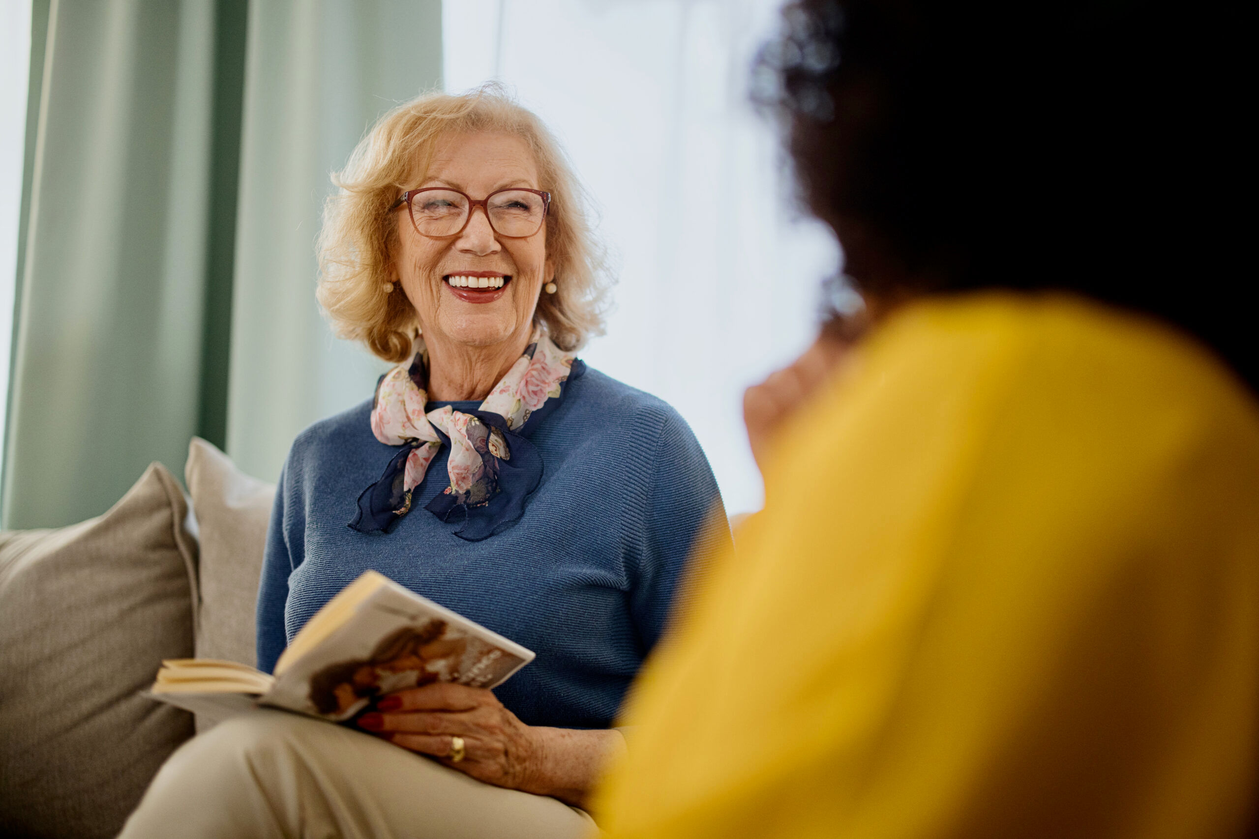 Group of people with a mixed age range talking and laughing while having a book club meeting.