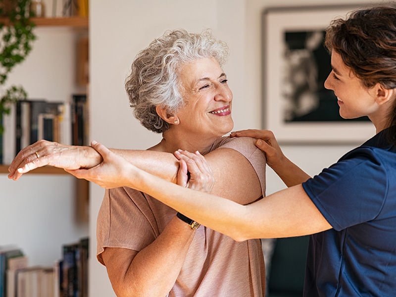 Older women stretching with the assistance of younger woman