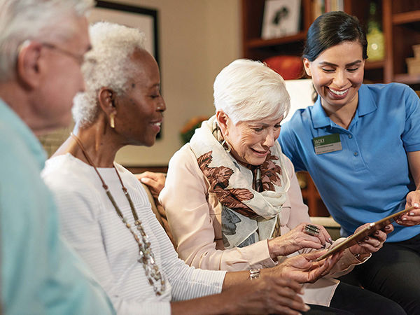 Three residents using a tablet with an Atria employee