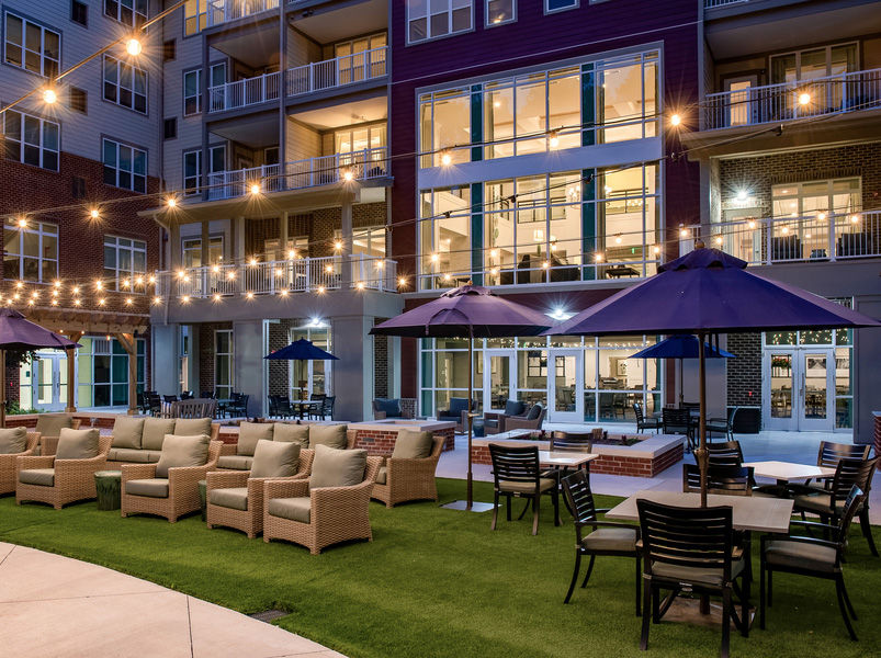 Atria Cary outdoor patio in the evening with multiple seating options and hanging lights