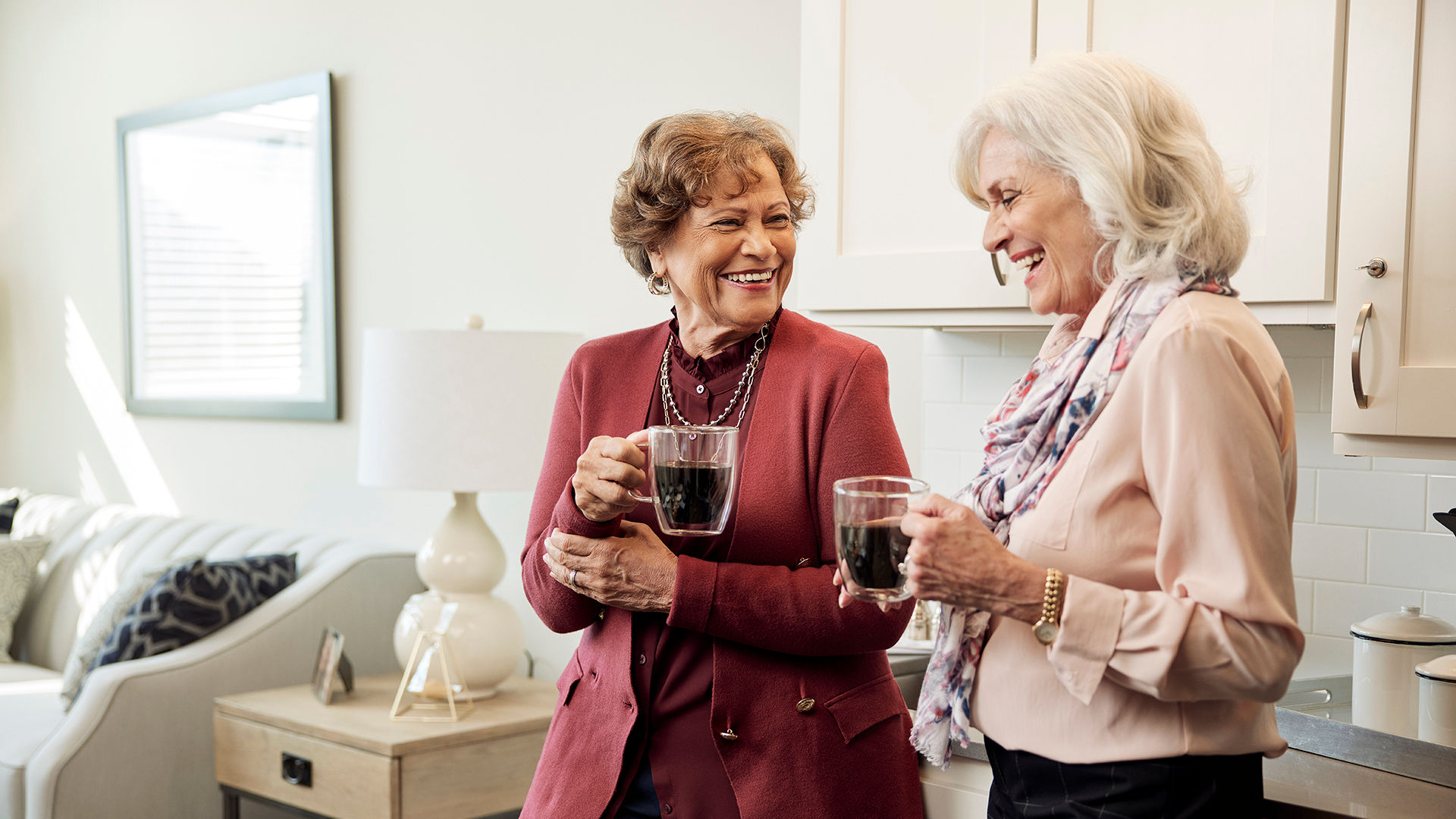 Two senior women having coffee in apartment