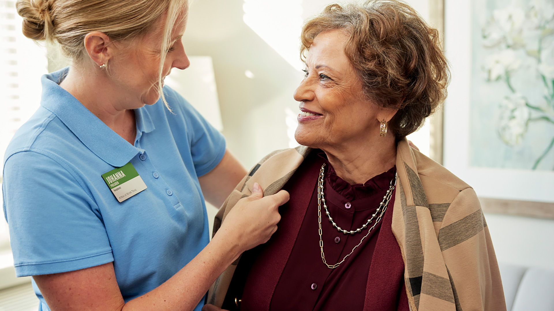 Caregiver assists senior woman with jacket