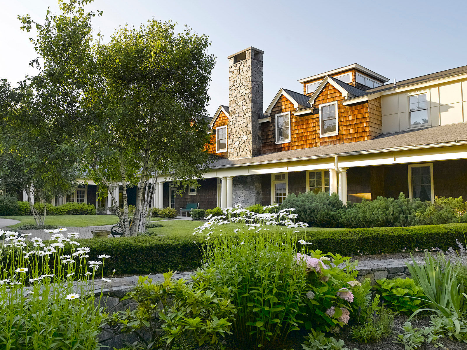 Atria Darien exterior showing a stone chimney, covered porch and flowerbed.