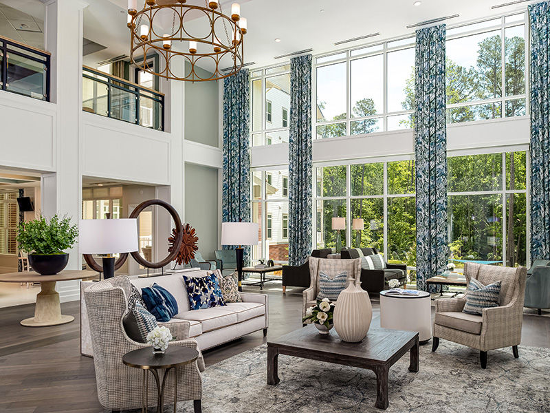 Brightly lit living room area with floor-to-ceiling windows, ornate pottery and fancy gray carpet and furniture