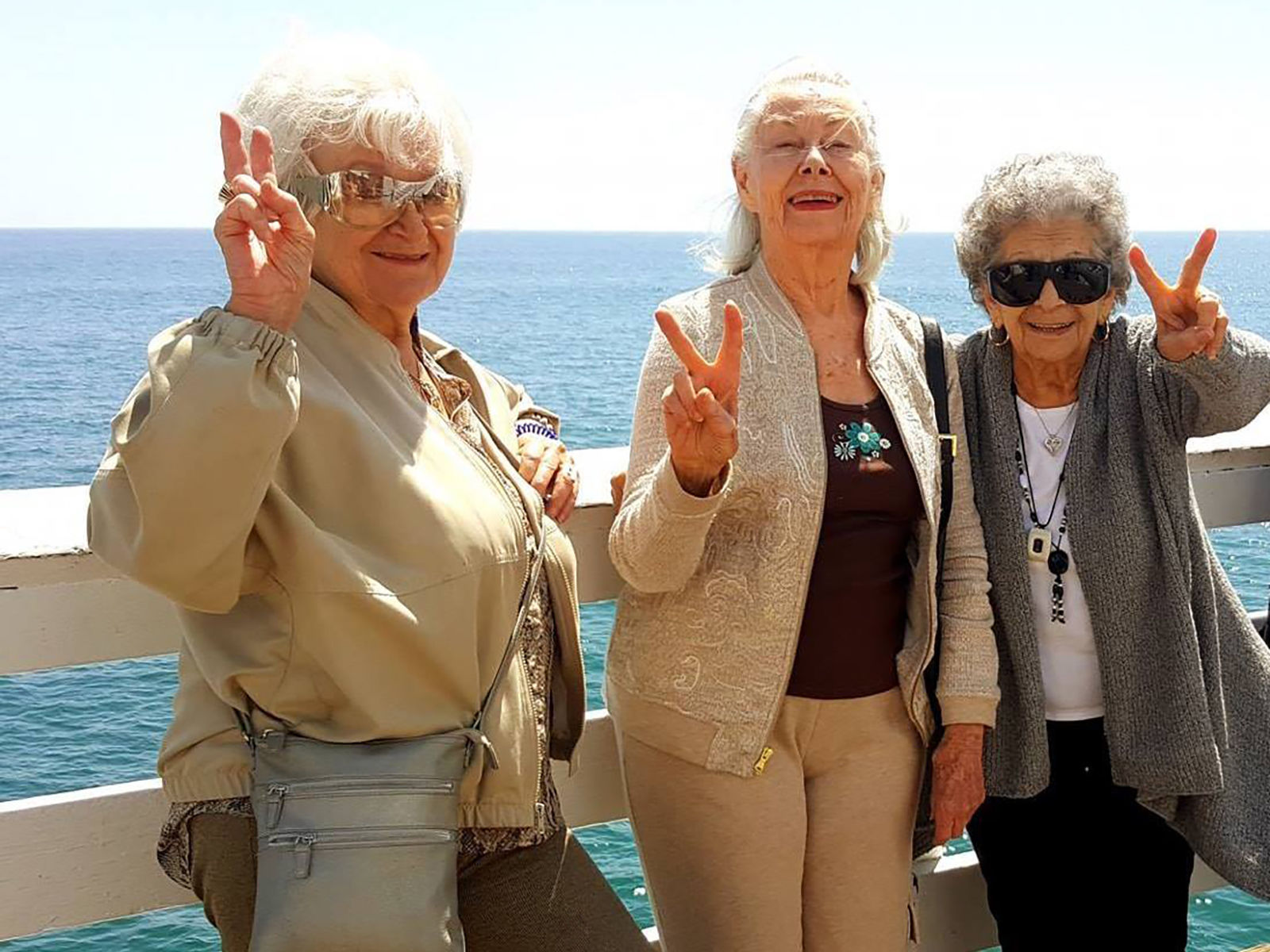 Three senior woman smiling for a photo on the pier