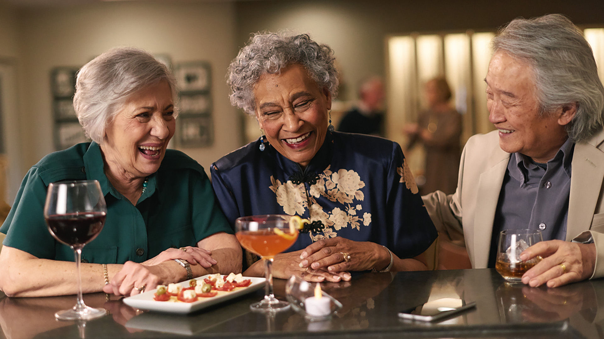 three senior friends enjoying wine and appetizers together