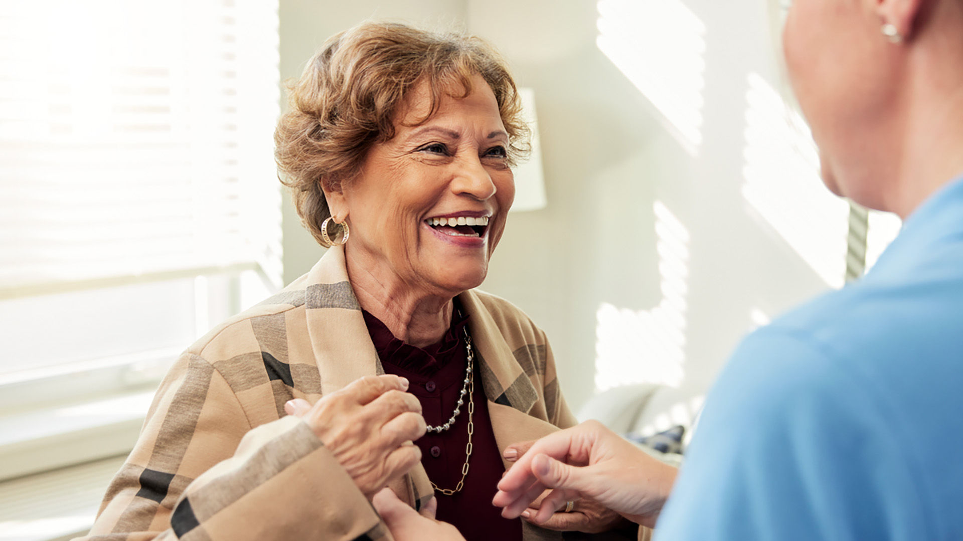 caregiver assisting senior woman with jacket