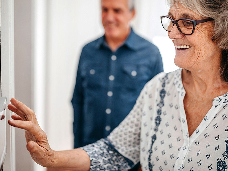 Senior woman using home automation touch screen panel in nursing home