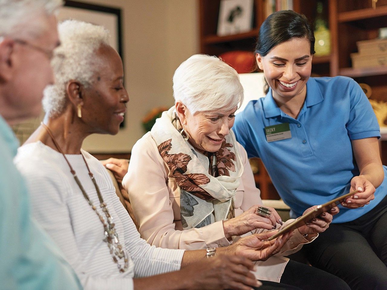 Atria resident uses a tablet with the help of fellow residents and Atria employee