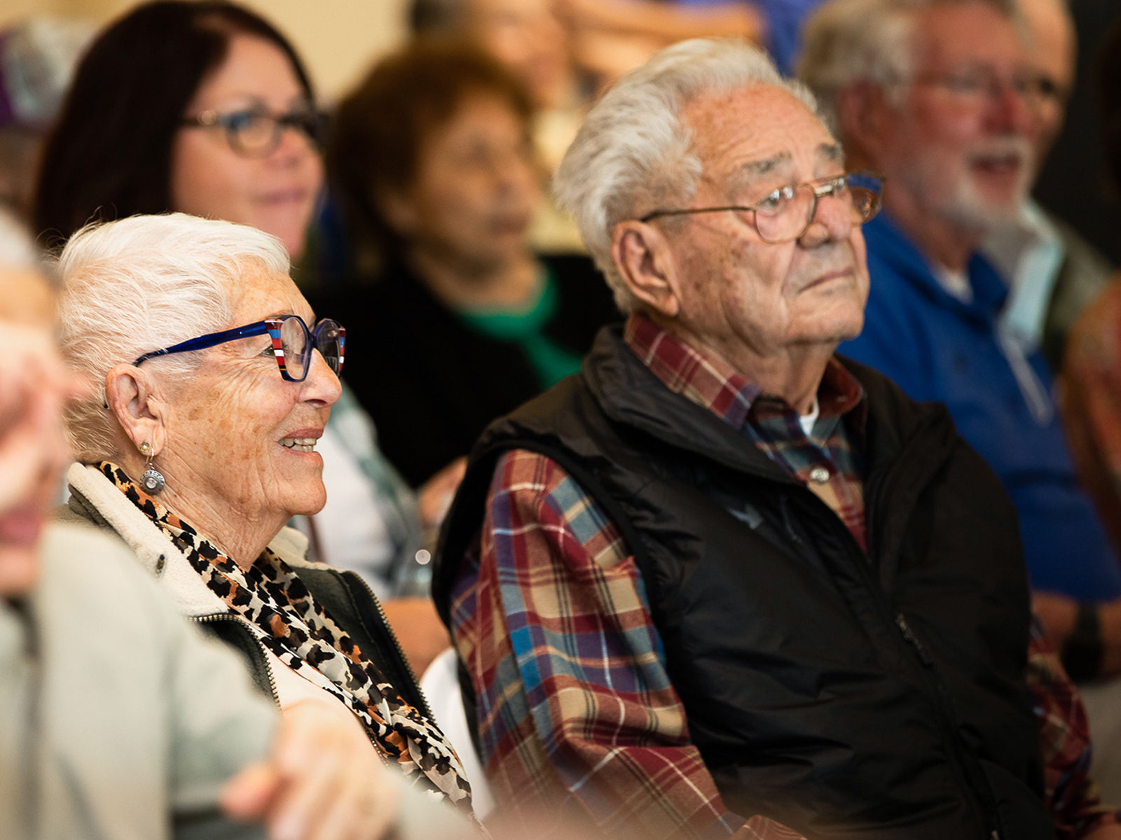 Older man and wife sitting in an audience and watching a lecture