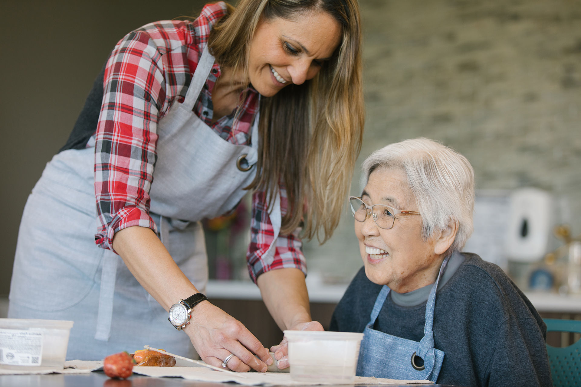 an instructor and a resident engaged in a senior living ceramics class