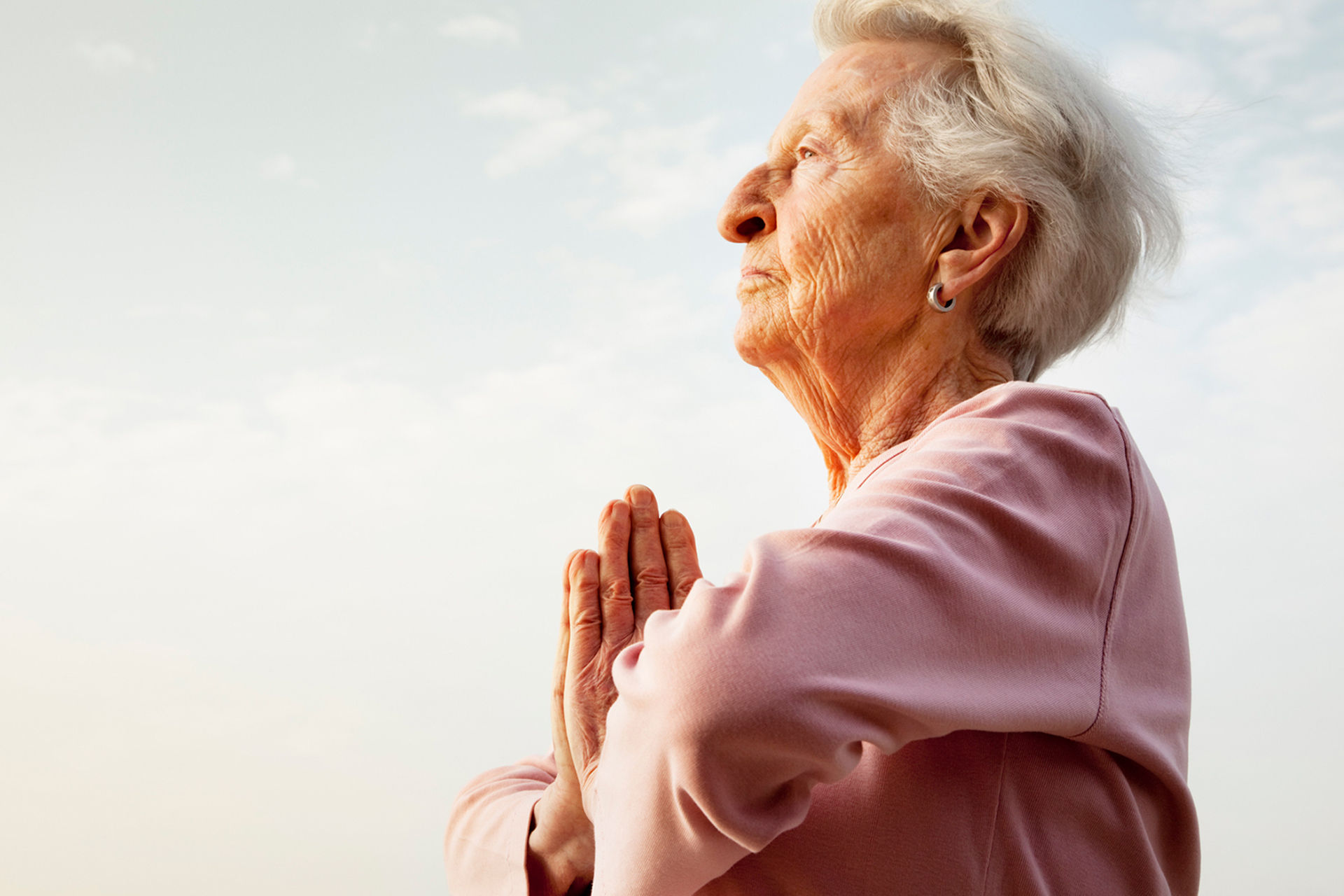 senior woman in meditative prayer stance outdoors at sunrise