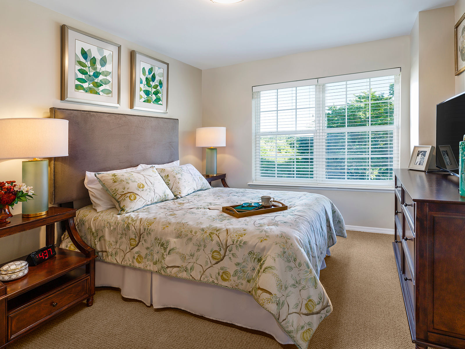 Bedroom adorned with oak furniture and a floral bedspread at Atria Plainview