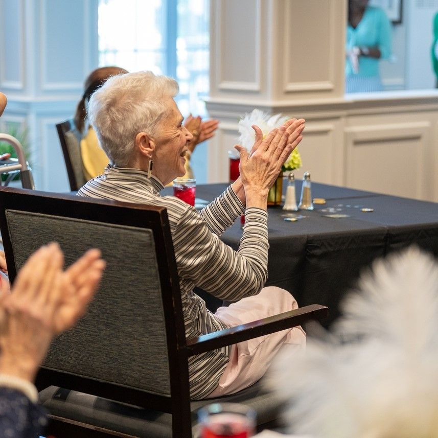 Focus on an older woman applauding within a group of audience members