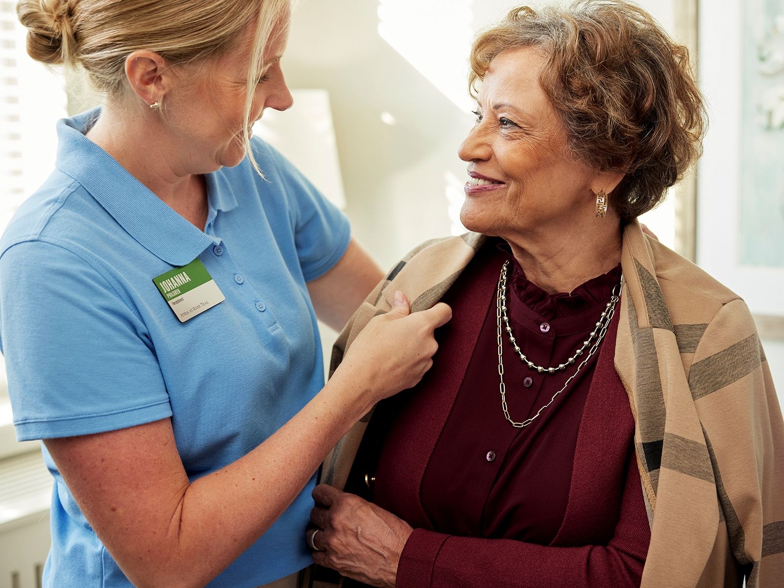 Atria employee helping a senior resident get ready in her assisted living apartment.