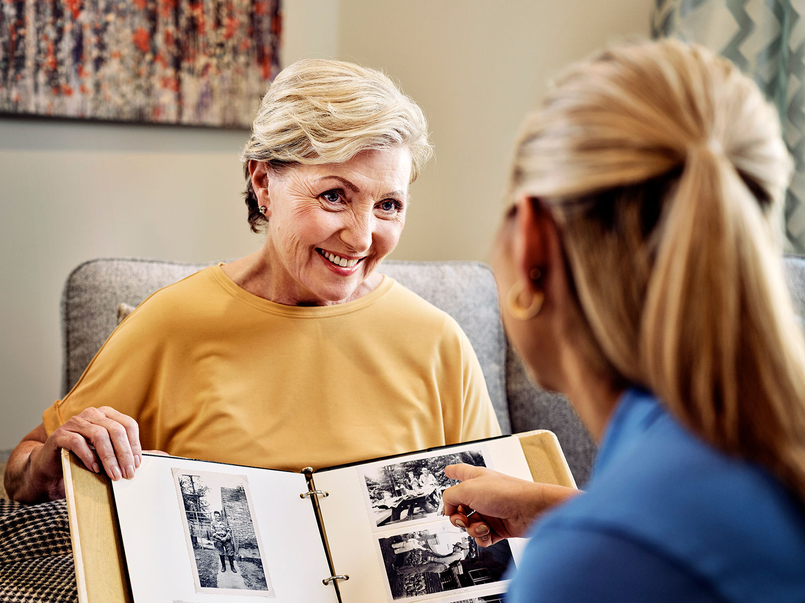 Senior woman showing photography to a memory care employee at an Atria Senior Living community.