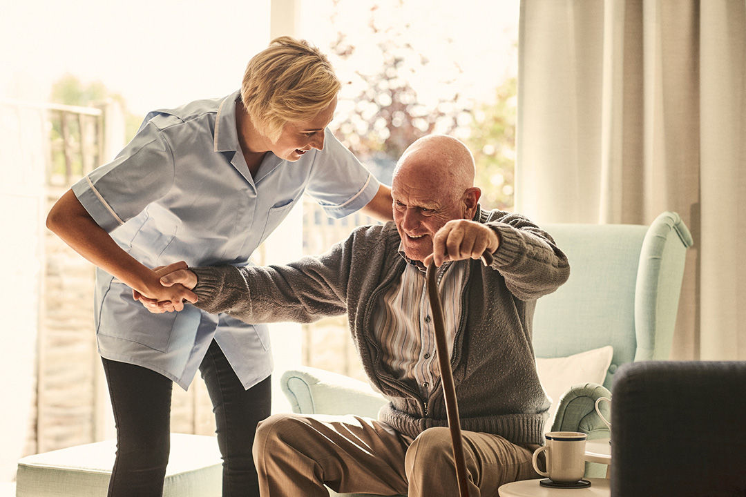 Senior man being assisted out of a chair