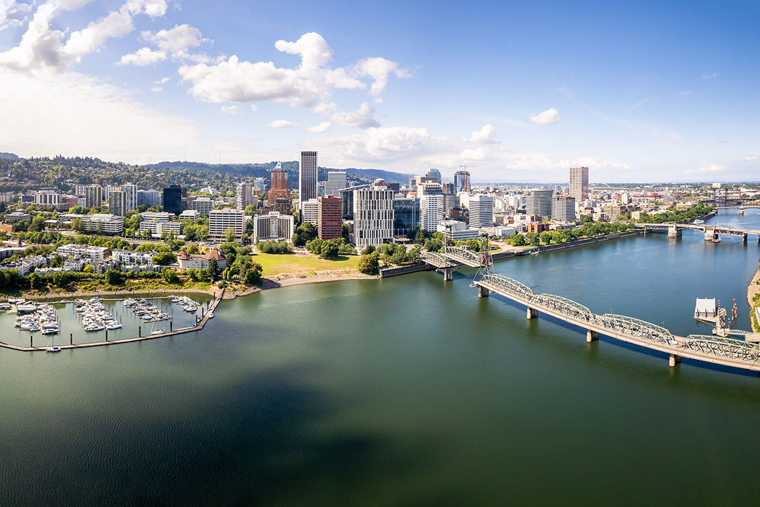 Aerial of Hawthorne Bridge on Willamette river in downtown Portland on a sunny day with views of the business district with skyscrapers and the Pearl district