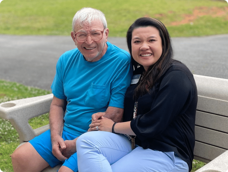 Younger woman sits on a bench with her aging dad