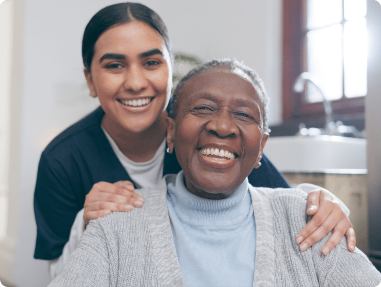 Older woman and younger nurse smile at the camera