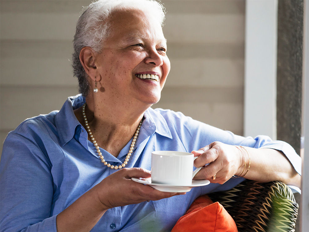 Femme âgée prenant son café sur sa terrasse