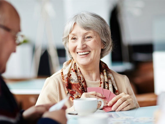 Femme plus âgée et homme jouant aux cartes et souriant